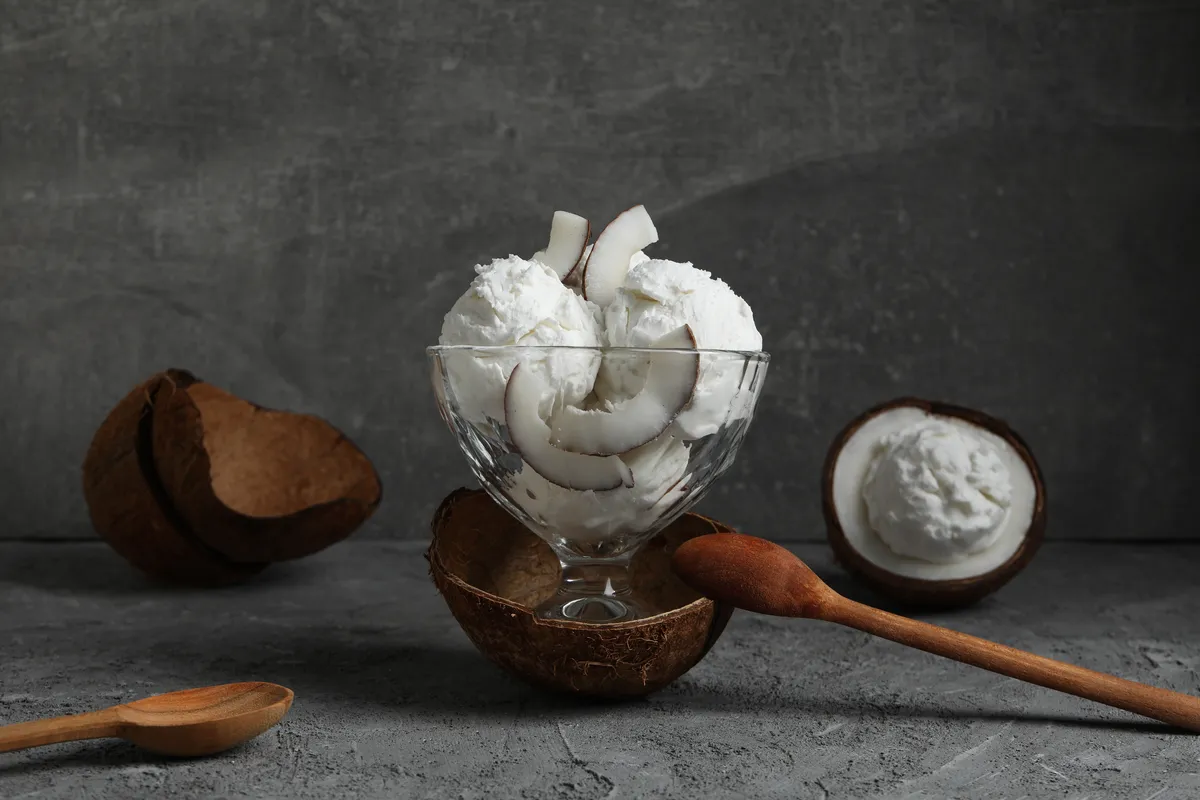 Scoops of coconut Iceolo sitting in a glass with shavings of coconut on top