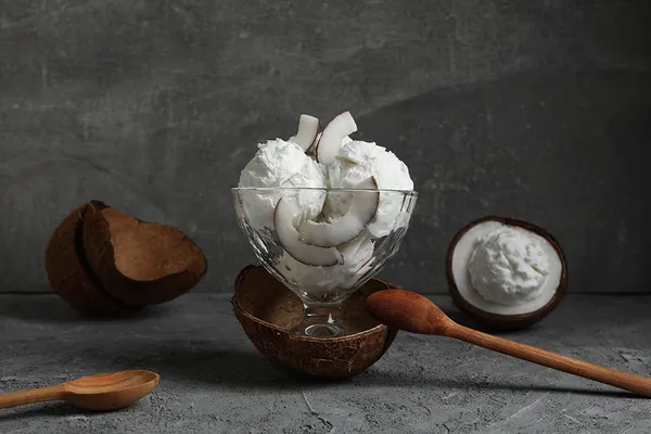 Scoops of coconut Iceolo sitting in a glass with shavings of coconut on top